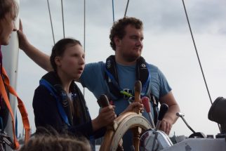 Two Crew Members Manning Helm with Adventure Under Sail
